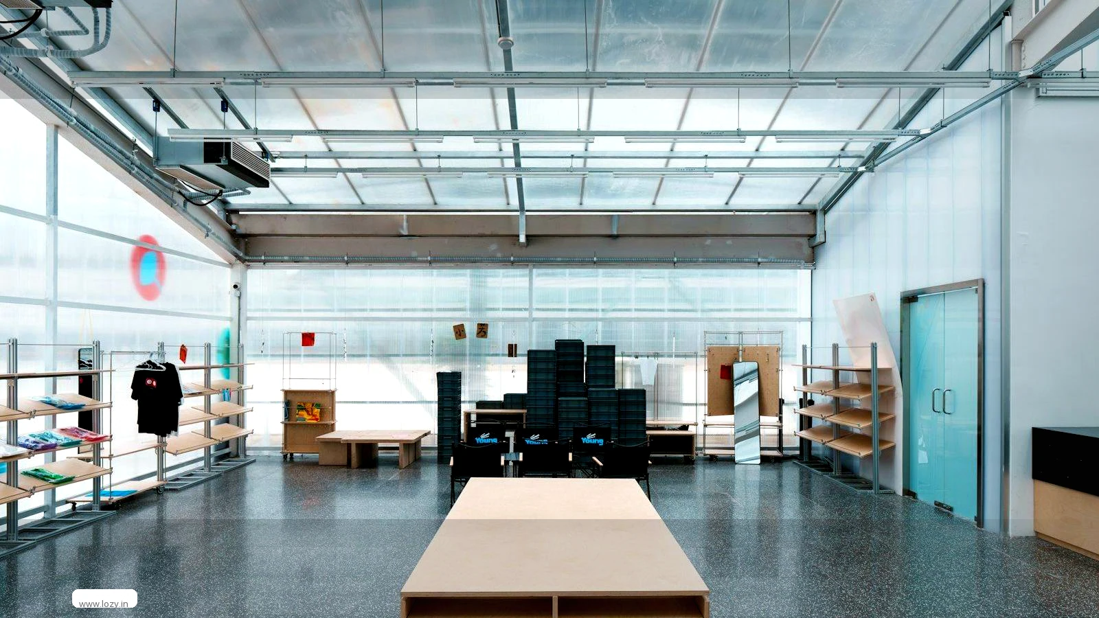 Empty Lozy warehouse bay in Dwarka, New Delhi, with blue-painted columns, a fan-cooled ceiling, marked flooring and a client's cartons stacked against the wall