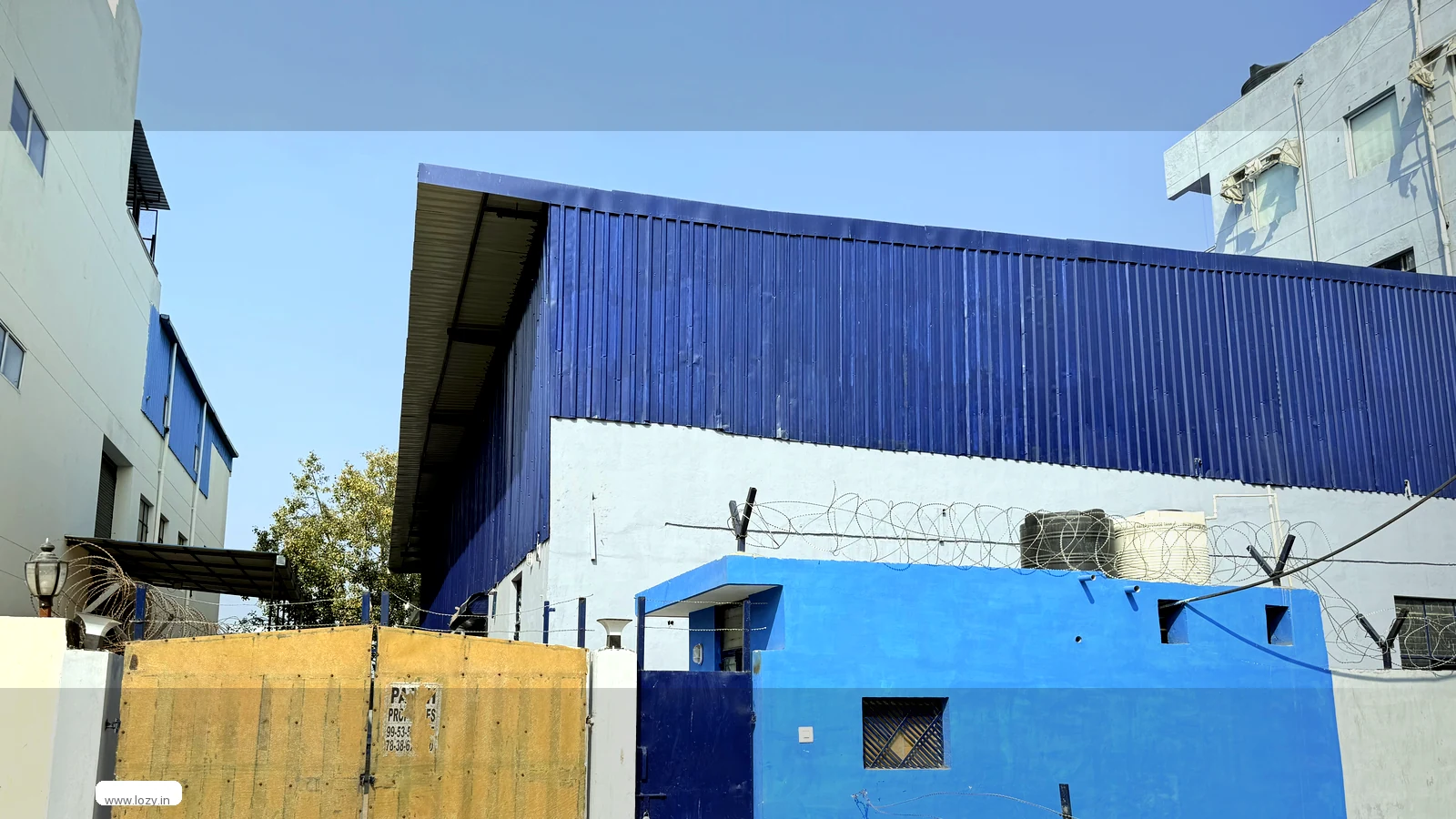Gated industrial warehouse compound at Mansar 5 on the Gurugram-Manesar belt, blue-clad shed with a roof overhang and a closed gate