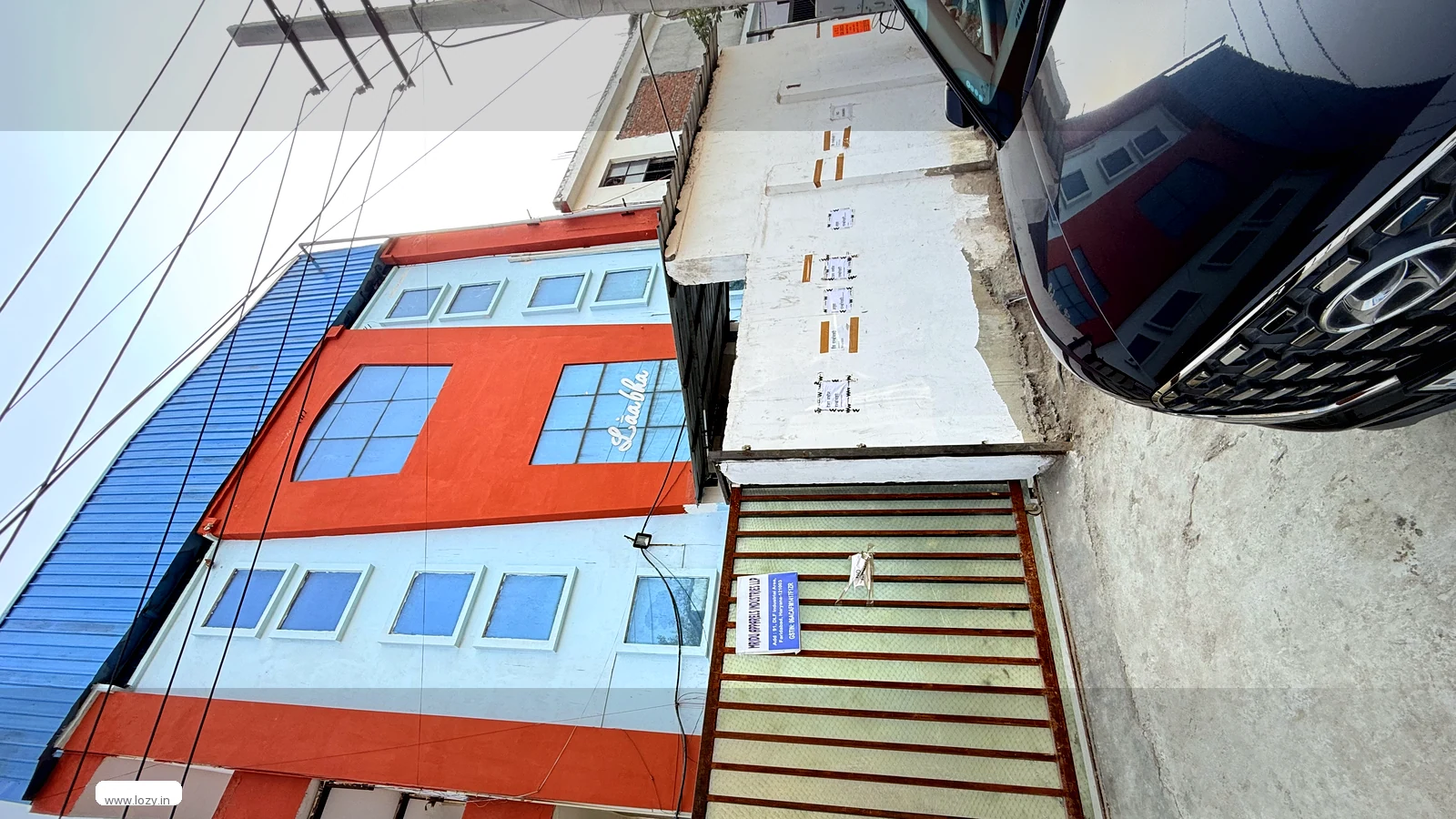 Gated industrial premises on the Faridabad DLF Industrial Area 1 belt with a concrete apron and a blue sheet roof behind