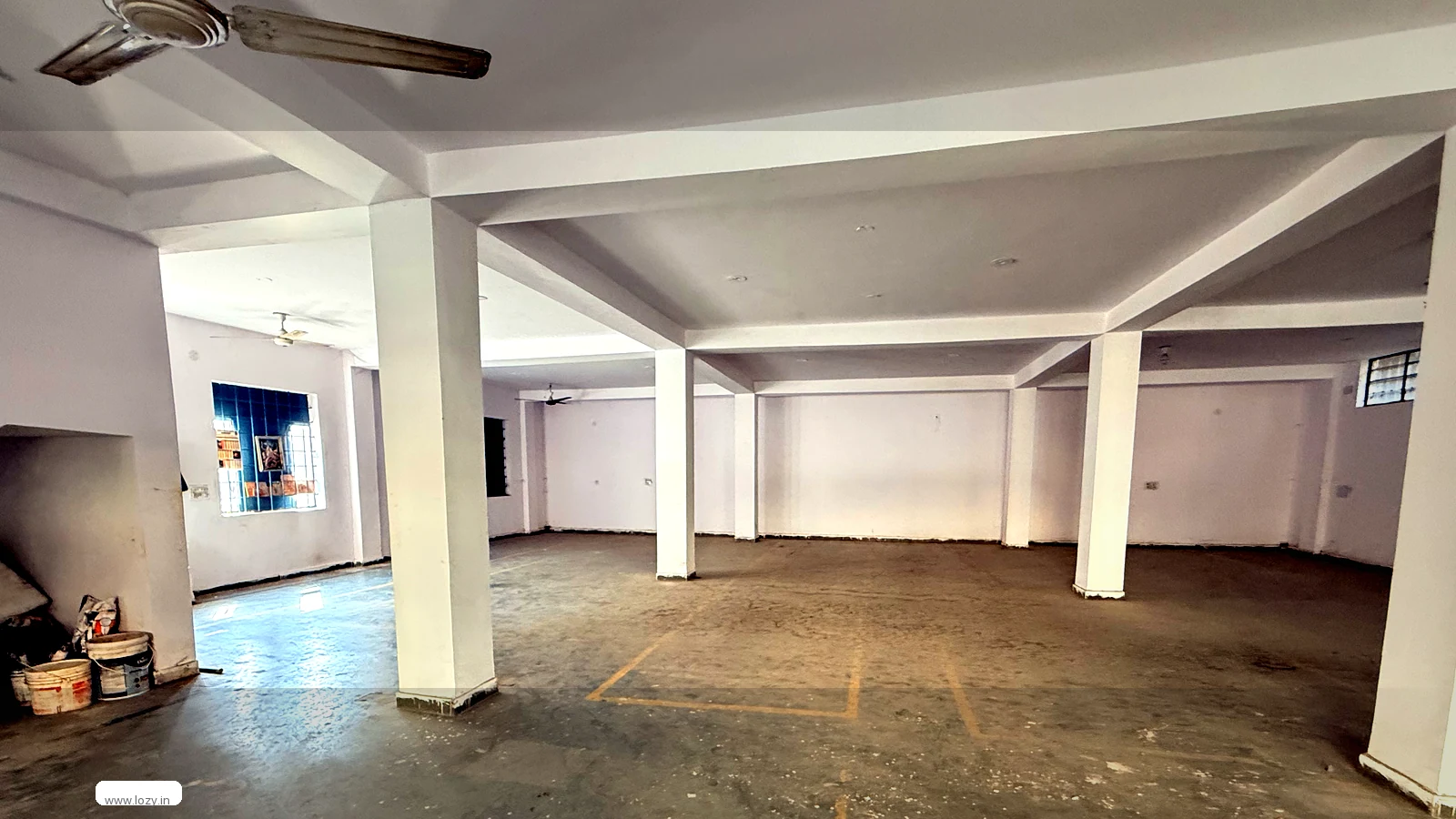 Lozy warehouse shed under fit-out at Manesar M-Zone, Gurugram - two roller-shutter loading doors under a metal canopy, concrete-block elevation and an unpaved approach yard