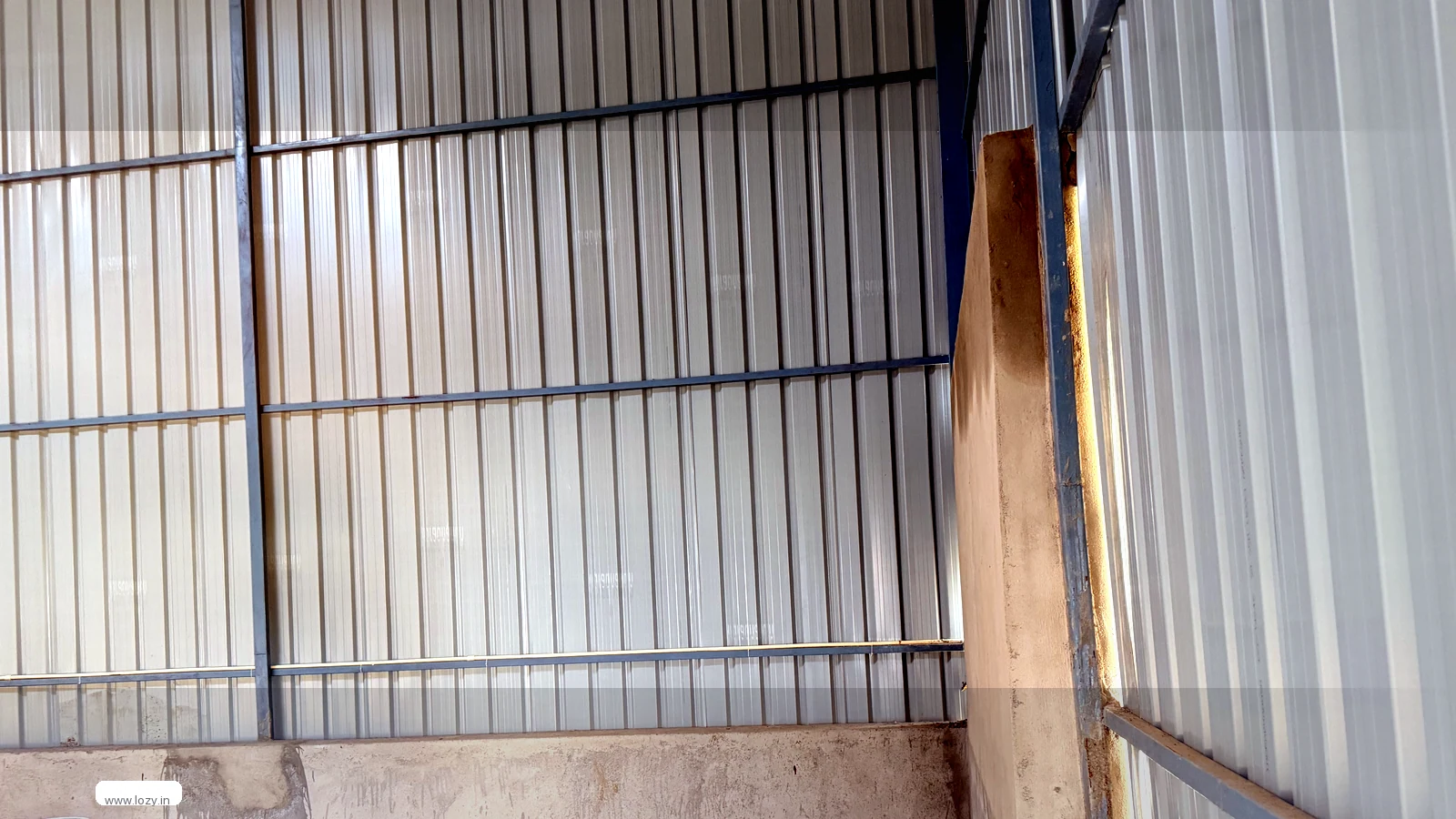 Warehouse shell at Kherki Daula, Gurugram belt - profiled metal cladding on steel purlins and a bare concrete floor awaiting racking