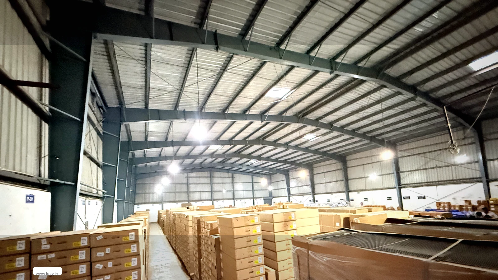 Electronics warehouse shed at Faridabad DLF Industrial Area 1 - clear-span steel truss roof and bare concrete floor
