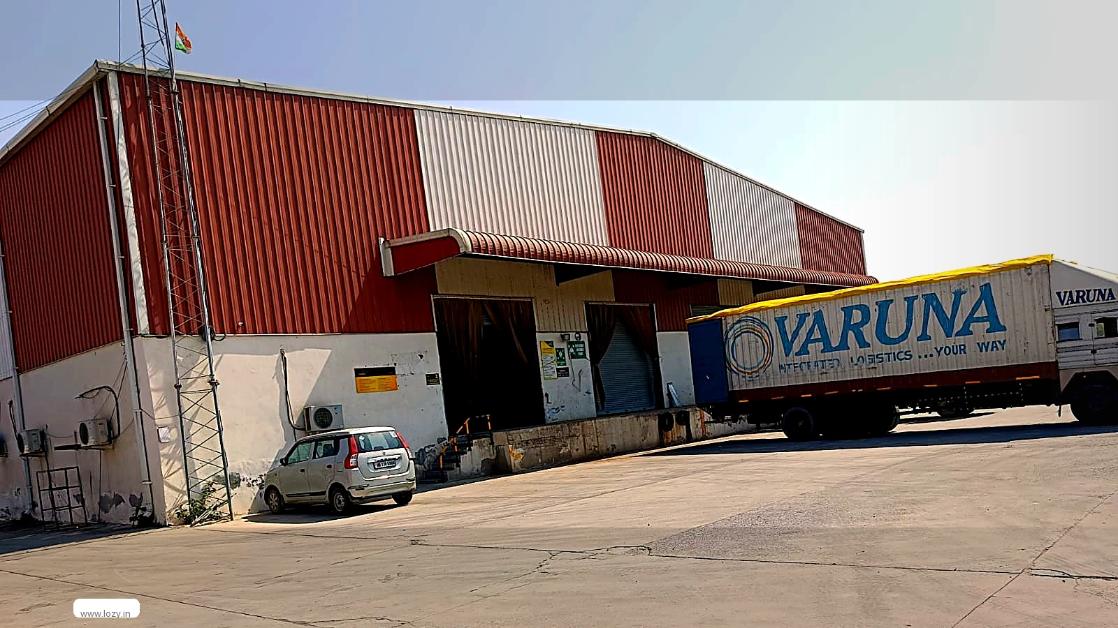 Warehouse gable elevation, paved yard and parked vehicles at a Lozy facility in Murthal, Sonipat, Haryana