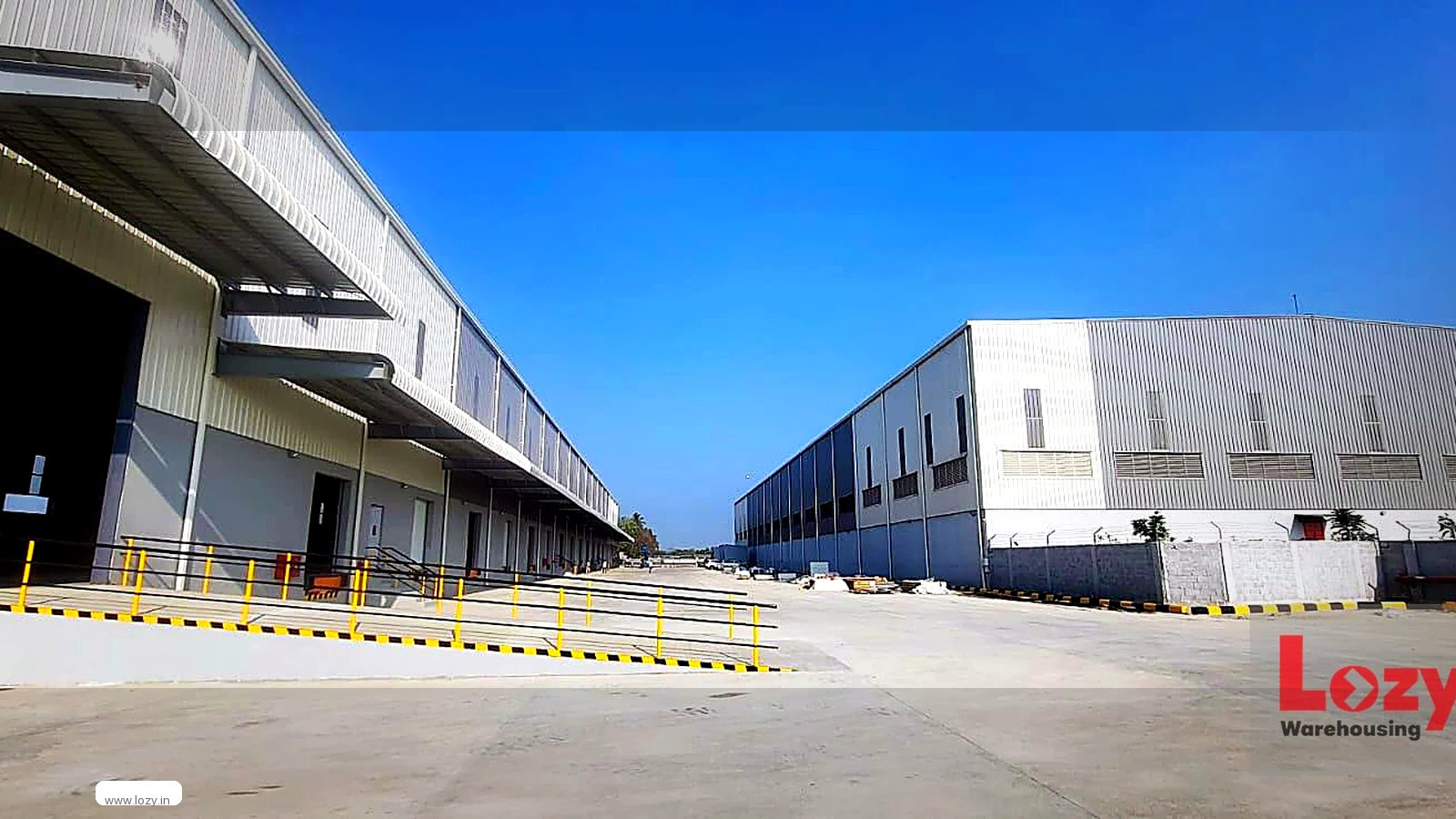Inside a Lozy warehouse in Chennai - clear-span steel roof, bare concrete floor and a row of stretch-wrapped palletised consignments along the wall