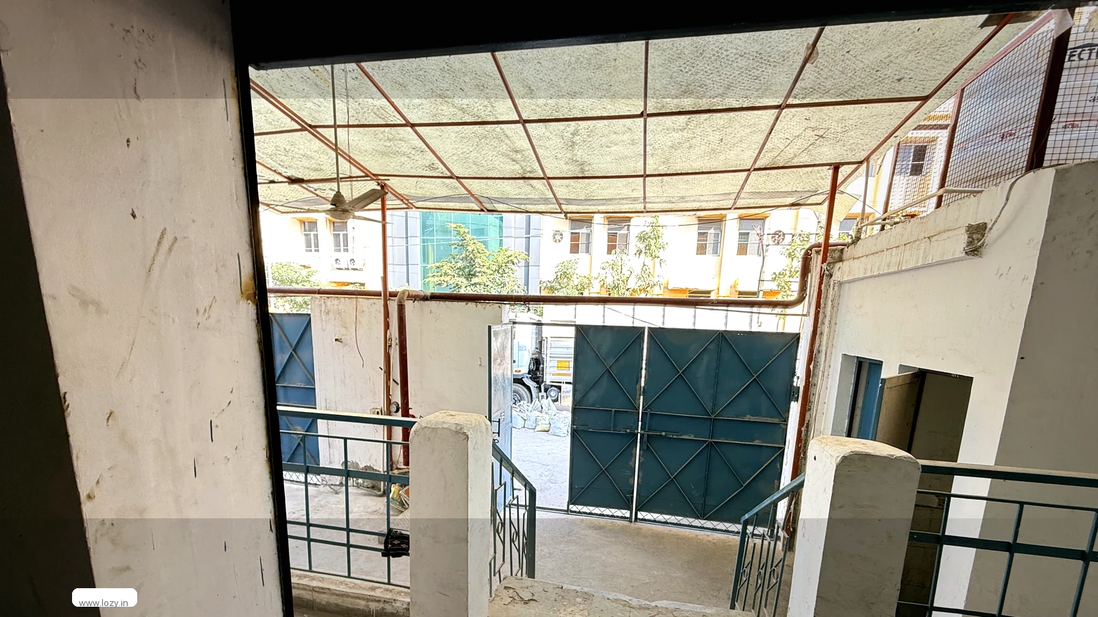 Empty clear-span Lozy warehouse shed at Mansar 5 on the Gurugram-Manesar industrial belt, with a high pitched roof on a steel truss frame and a bare concrete floor before fit-out