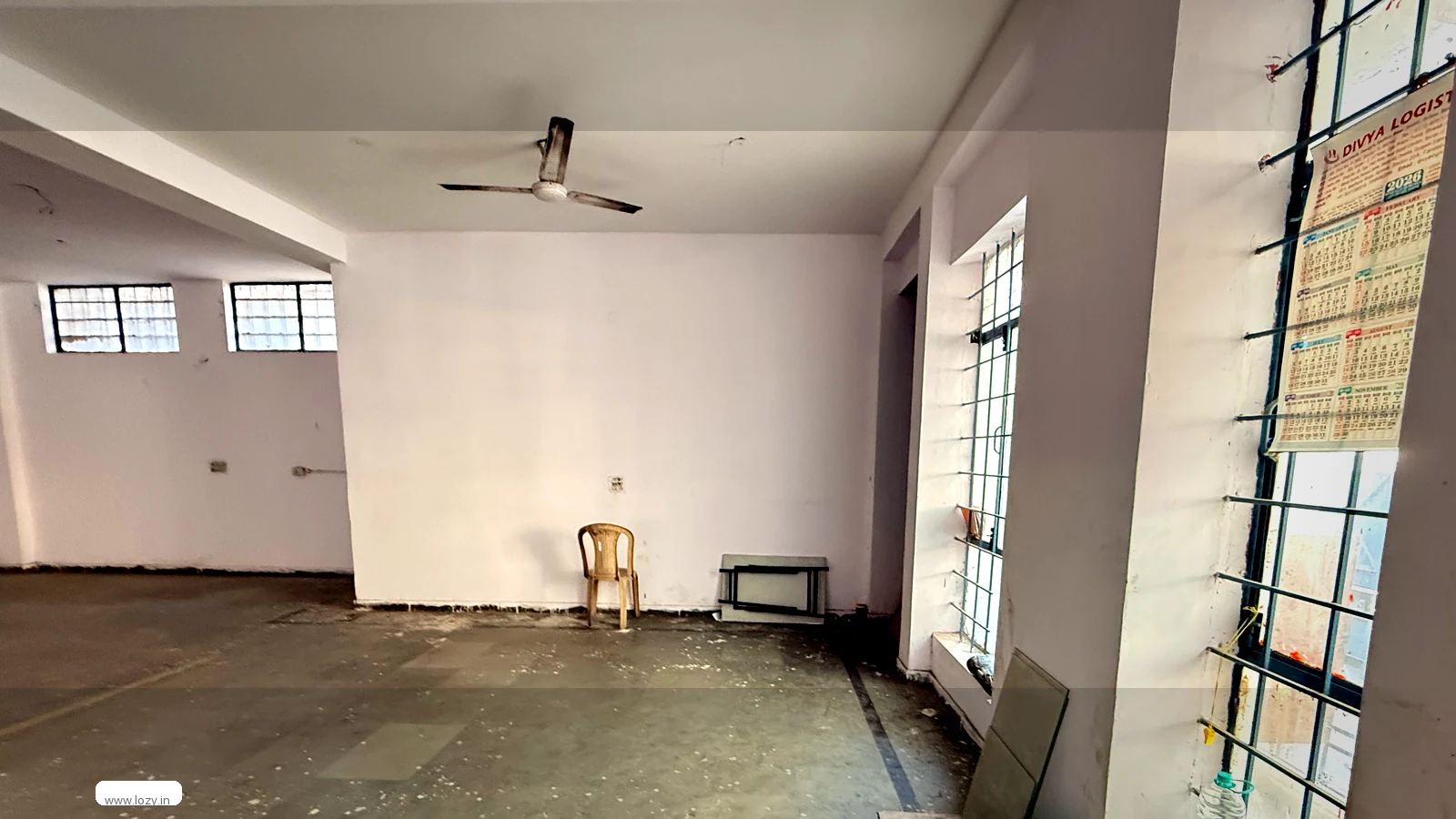 Empty Lozy warehouse bay in Faridabad Industrial Area 2 - white painted walls, gridded steel windows and the bare grey slab before racking goes in