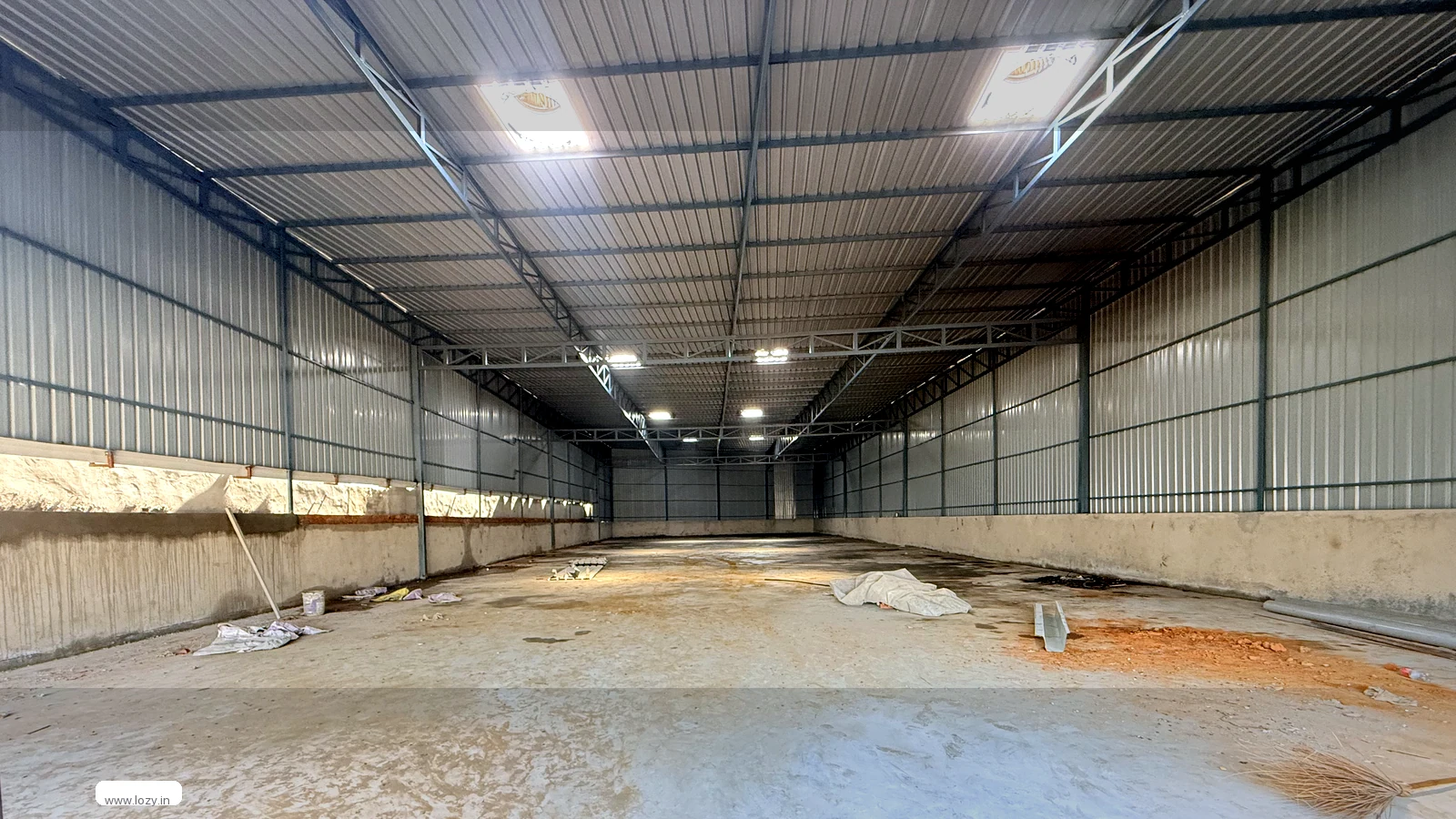 Empty clear-span warehouse with a steel truss roof and sealed concrete floor at Manesar M Zone, Gurugram, ready for gym equipment floor bays