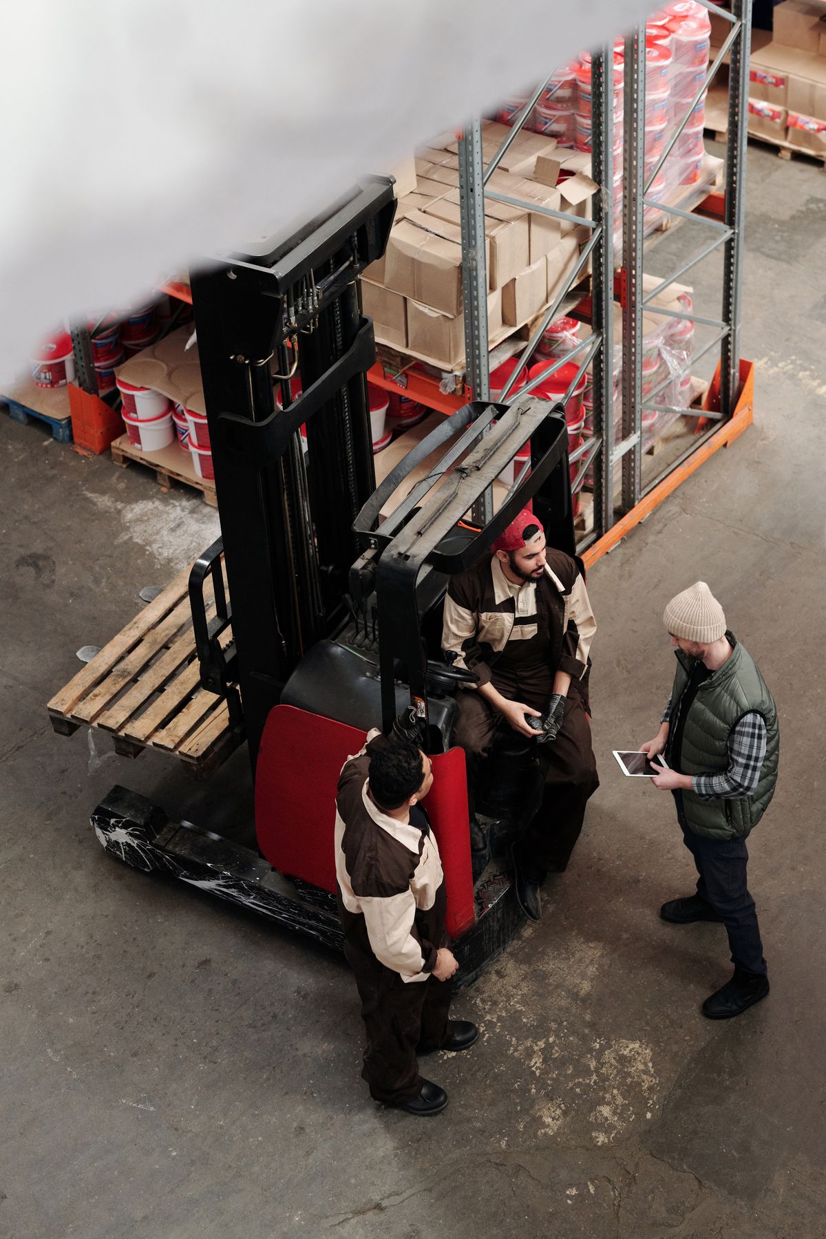 Warehouse team briefing beside a forklift and pallet racking