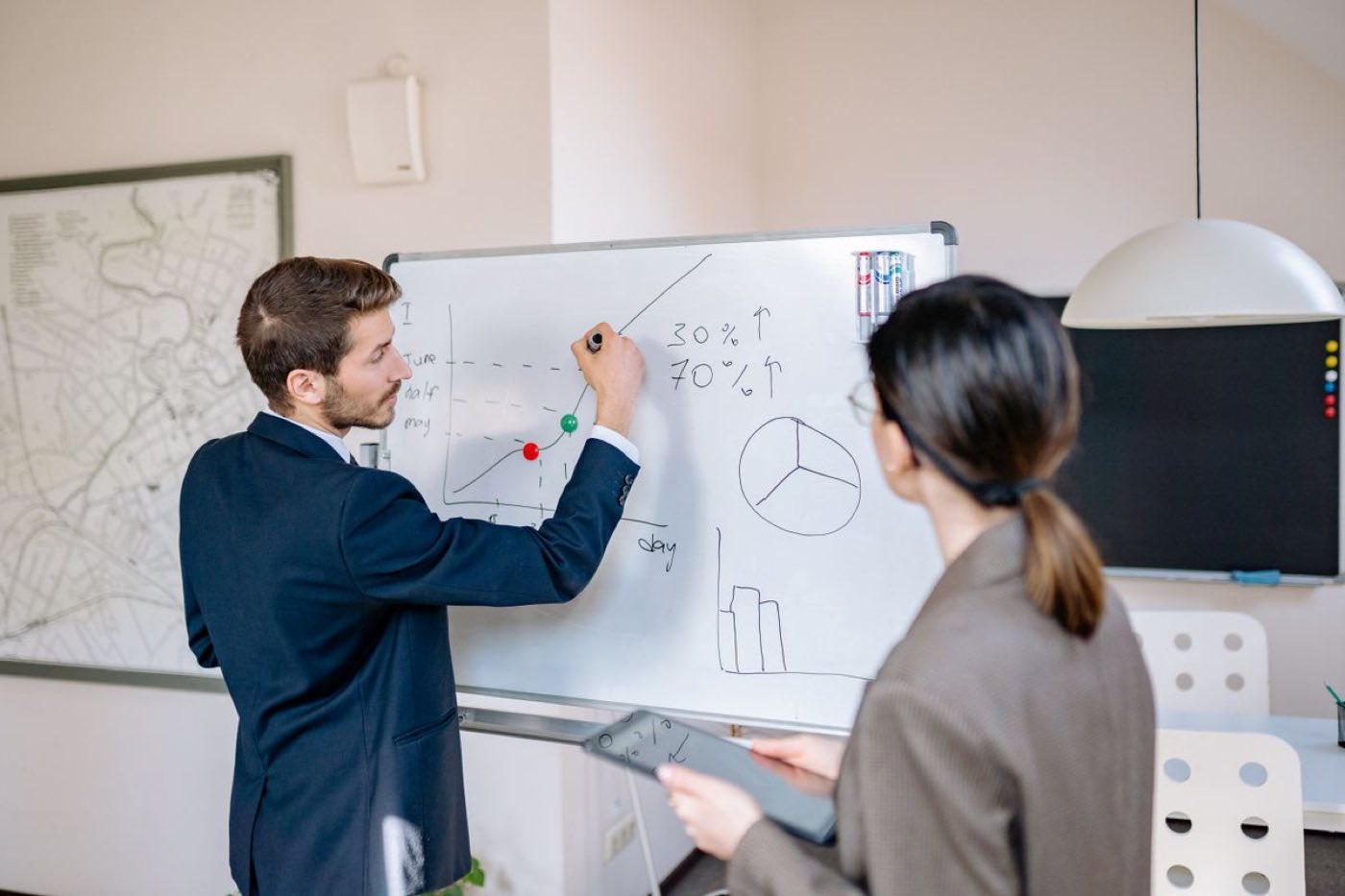 A business consulting session at the Lozy desk: two professionals work through network charts and cost graphs drawn on a whiteboard in Delhi NCR